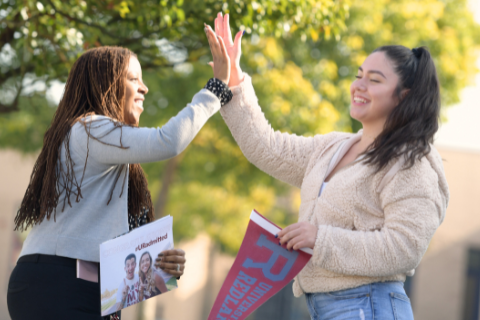 Two young college students give each other a high five.