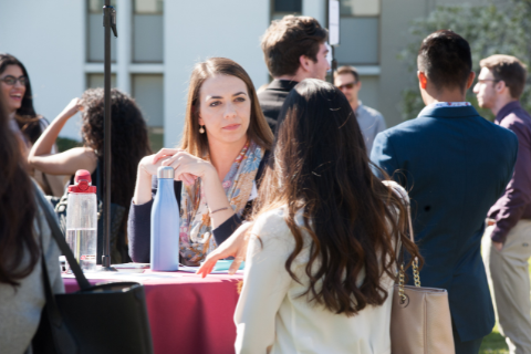 A student talks to an employer at a career event outdoors.