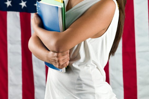 A Latina holds folders and notes in front of the US flag
