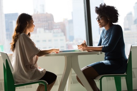 two women talking at conference table