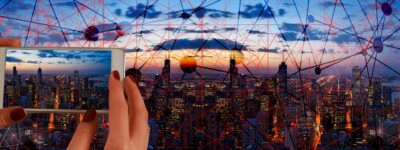 Hands holding cellphone taking photo of cityscape with matrix overlay