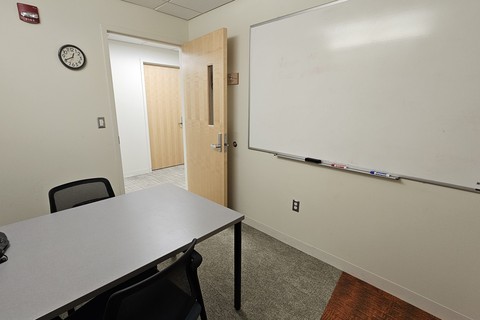 CAPD interview room image that features a table, 2 chairs, dry erase board, and a table top phone