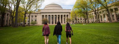 Three students walking toward the MIT dome on a sunny early autumn day.