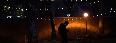 A person walking across the MIT campus at night while reading their phone.