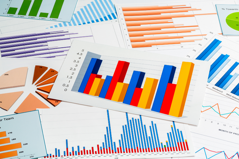 several colorful printed bar graphs and charts, laid out on a table