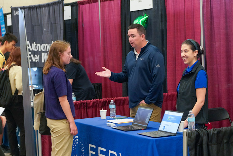 2 employers speaking to a student at their booth at the fall career fair fcf