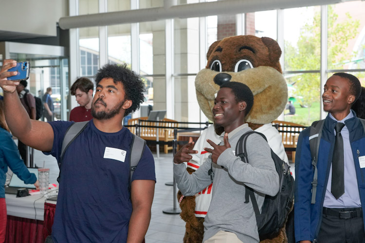 Three students taking a selfie with Tim the MIT Mascot at the fall career fair-fcf