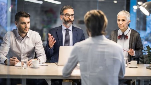 one person being interviewed by three others in an office setting