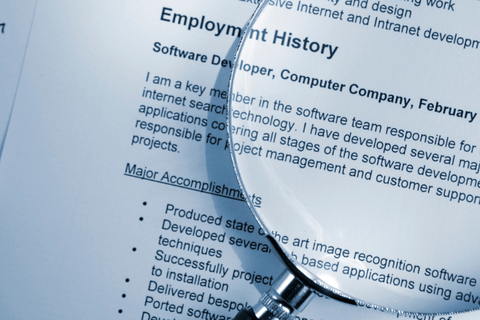 a magnifying glass sits on top of a resume