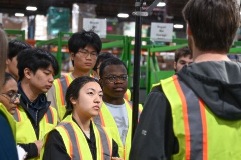 Group in yellow vests on factory floor talking