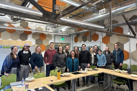 A group of people standing around a table and smiling at the camera