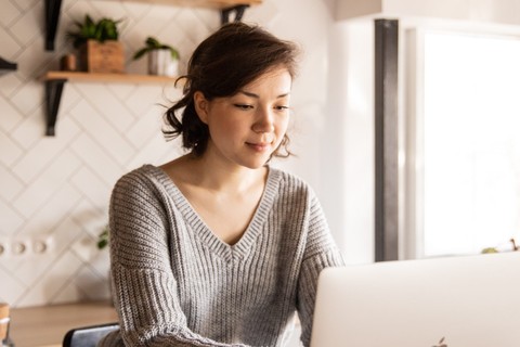 girl in grey sweater looking at laptop