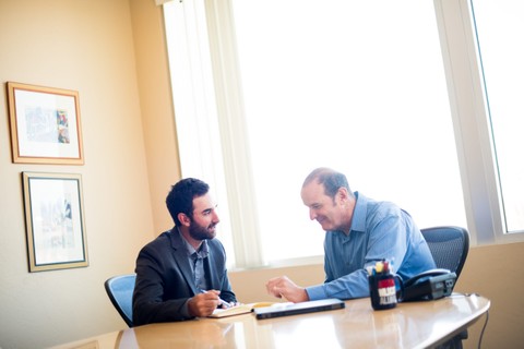 two men in suits sitting at a conference table