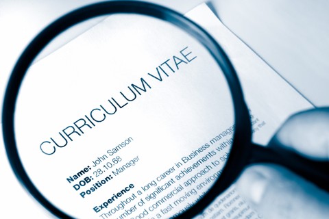 magnifying glass reviewing a curriculum vitae