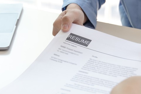 person submitting a resume across a desk