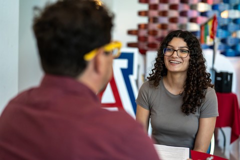 Female identifying student sitting and talking with a professional.