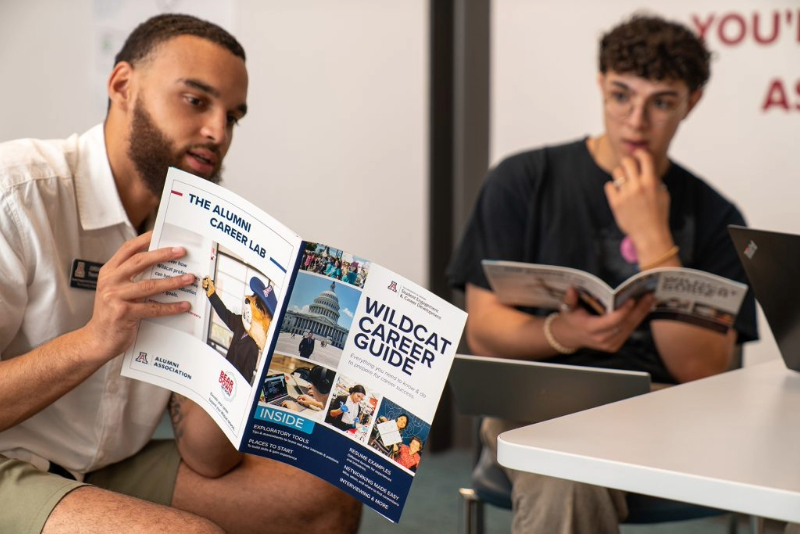 A man shows the Wildcat Career Guide to a student.