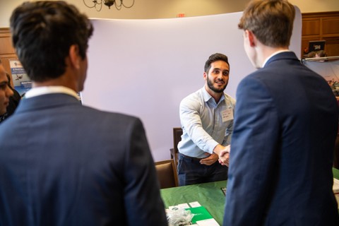 Two students networking with an employer.