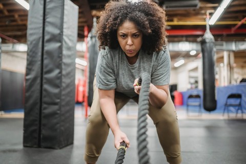 Woman exercising by lifting ropes
