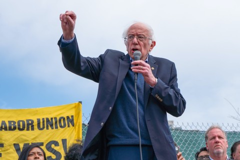 Sen. Bernie Sanders speaking to a crowd, holding a microphone