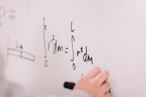 Hand writing math equation on a whiteboard