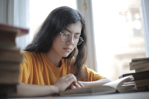 Person wearing glasses reading a book