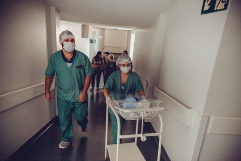 Medical staff transport a baby in a hallway