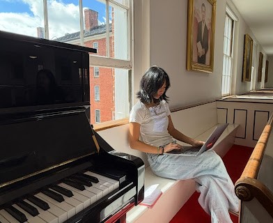 Rebekah Hong, not pictured, playing piano while friend Clarissa types on a laptop next to the piano