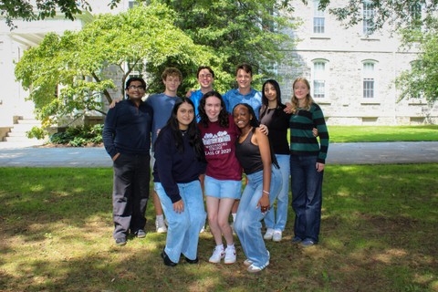 Group photo of Career Interns, standing outside on a grass field.