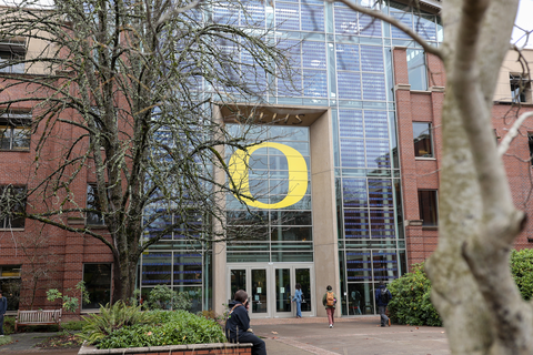 Exterior shot of the Lillis Business Complex on a wintery day. Students walk through the front doors beneath the iconic yellow