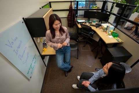 A student and career mentor meet in a small office, brainstorming ideas written on a whiteboard.