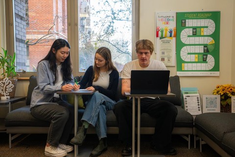 Three students sit on a couch working on their career goals. Some are reviewing resumes and another is on a laptop, while in the Mohr Career Services suite.