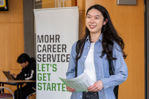 Close-up of student walking out of the career center looking confident with a piece of paper in her hand
