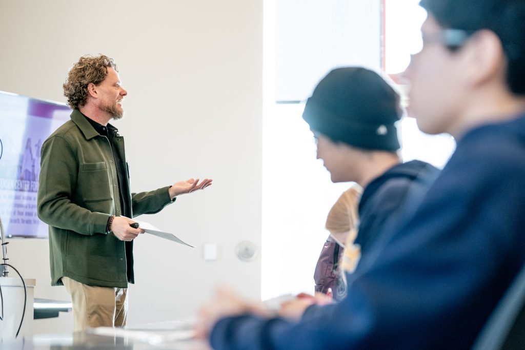 A professor stands in front of a classroom.