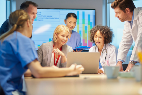 group of medical professional talking around a laptop.