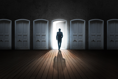 siloutette of a figure walking through an open doorway in the center.