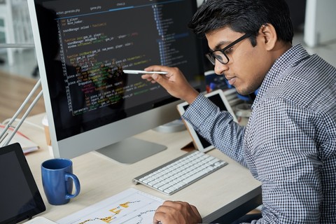 Student sitting at a computer reading a paper in front of him