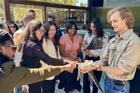 UF students pet a small gator held by a staff member at Gator Spot.