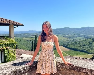 Delaney Johnson stands on a stone terrace overlooking the rolling hills of Italy, during her study abroad experience