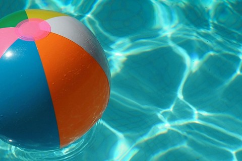 A beach ball floats on a sunlit pol