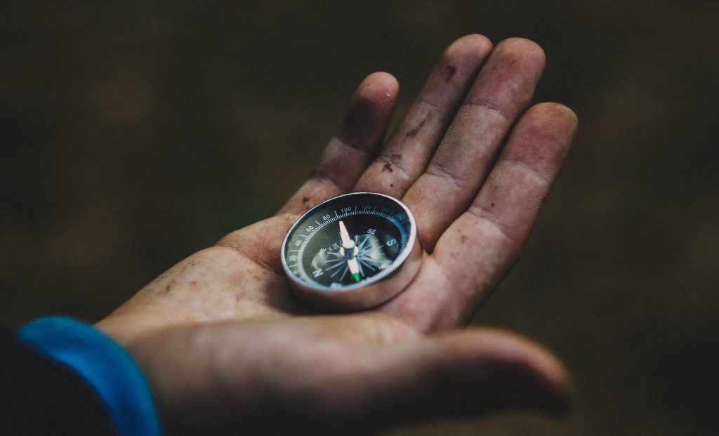 A hand holding a compass.