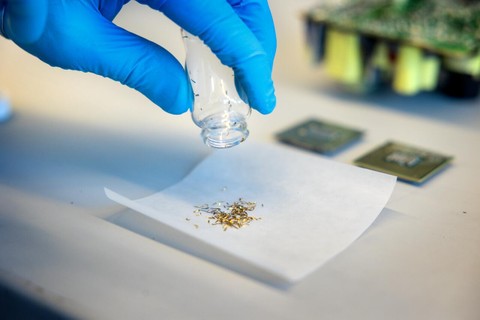 A gloved hand shakes gold from a bottle on to a desk.