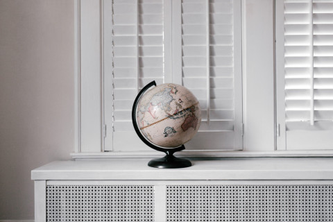 Picture of a globe on a radiator shelf in front of a window.