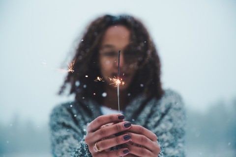 A woman holding a sparkler in the snow.
