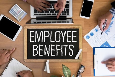 Chalkboard with Employee Benefits on it staged next to an open laptop.