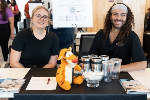 Two smiling employers sitting at a table with a Tigger stuffed animal