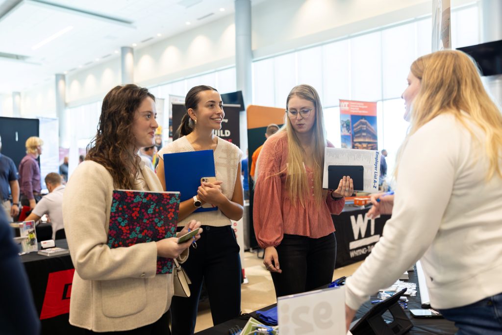 students speaking with an employer at a booth during a career fair