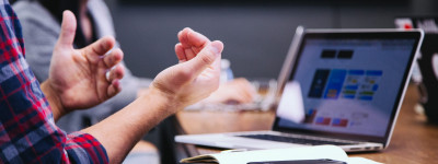 close up of two people at a desk with a laptop