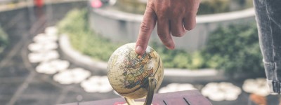 close up of person putting finger on a small globe