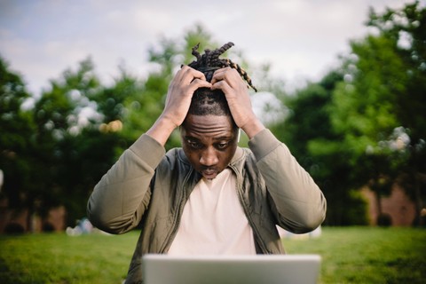 Man holding head looking at laptop.